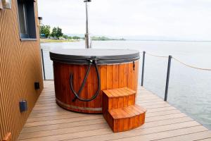 a large wooden barrel sitting on a dock next to the water at Houseboat Glamour & wellness in Kaluža