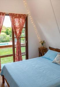 a bedroom with a blue bed and a window at Cabañas Don Luis in Valle Hermoso
