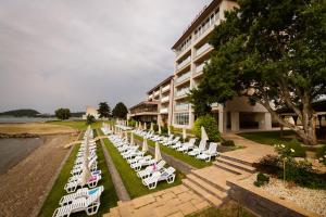a row of white lounge chairs in front of a building at Houseboat Glamour & wellness in Kaluža