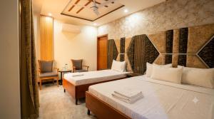 a hotel room with two beds and a chair at Standard Elite Palace inn Hotel in Islamabad