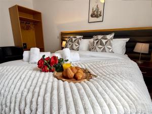 a tray of bread and flowers on a bed at Maya Hotel in Luton