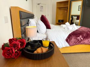 a bedroom with a bed and a tray of food on a table at Maya Hotel in Luton +78 photos