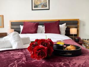 a bed with red roses and a tray of food at Maya Hotel in Luton