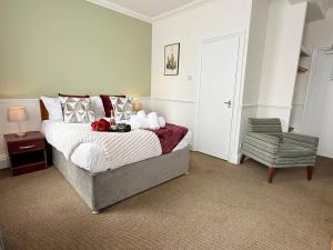 a bedroom with a large bed and a chair at Maya Hotel in Luton