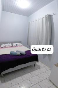 a bedroom with a bed with a purple blanket at Pousada familiar 07 in Rio do Sul