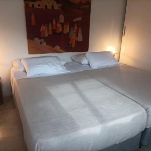 a large bed with white sheets and pillows in a room at La casita anaranjá in Villa Allende