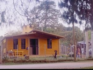 a woman walking in front of a yellow house at Cabaña Abigel in Zacatlán +2 photos