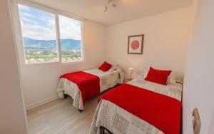 a bedroom with two beds and a large window at Oceana Suites Papudo in Papudo