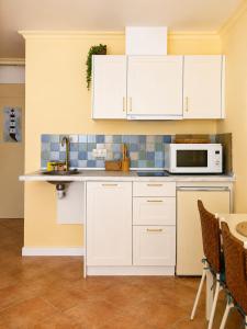 a kitchen with white cabinets and a microwave at Holibai Misiño, Estudio para dos en Baiona in Baiona