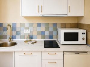 a kitchen counter with a microwave and a sink at Holibai Misiño, Estudio para dos en Baiona in Baiona