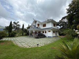 a white house with a car parked in the driveway at Bamivigas Retreat in Kattappana