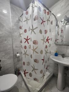a bathroom with a shower curtain with seashells and a sink at Ande Tower, Batumi in Minda +7 photos