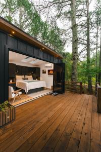a bedroom in a modern house with a wooden deck at Luxury tiny cottage with deck hammock and hot tub! in Guntersville