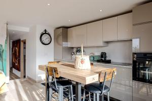 a kitchen with a wooden table and a clock on the wall at Entre lac-montagnes et frontière in Contamine-sur-Arve