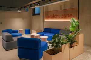 a waiting room with blue furniture and a sign that reads comfort zone at Homaris K48 Studios in Berlin +33 photos