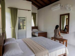 a woman sitting in a bedroom looking in the mirror at Forest & Fields Sinharaja in Deniyaya +148 photos