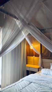 a bedroom with a canopy bed and a yellow bench at Ekas Rising Coffee And Cottages in Ekas +3 photos
