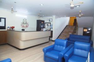 a waiting room with blue chairs and a counter at Hotel Srinivas in Cochin