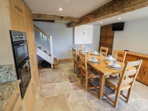 a kitchen and dining room with a wooden table and chairs at Netherend Barn in Colwall +15 photos