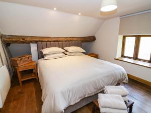 a bedroom with a white bed and a wooden floor at Netherend Barn in Colwall