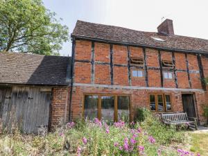 an old brick house with a bench and flowers at Netherend Barn in Colwall