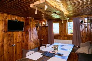 a dining room with a table and a tv on a wooden wall at Вила Якимови in Ribarica