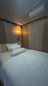 a large white bed in a small room at Ekas Rising Coffee And Cottages in Ekas