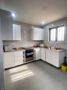 a kitchen with white cabinets and a stove top oven at Maisonette near Alpha Beach in Ibeju