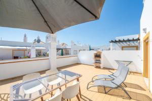 a balcony with a glass table and chairs on a roof at Quinta da Gomeira by Algartur in Cabanas de Tavira