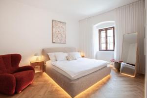 a white bedroom with a bed and a chair at Pension Marie in Český Krumlov