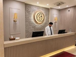a man standing at a reception desk in a hotel lobby at Shelton's Rezidor Peshawar in Peshawar