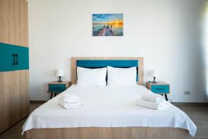 a bedroom with a large white bed with two blue tables at Kazeboo Bed & Breakfast in Mamaia Sat/Năvodari +132 photos