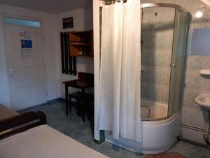 a bathroom with a shower and a bed and a sink at Hangya panzió in Târgu Secuiesc