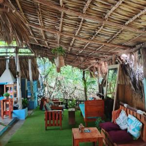 a living room with a thatched ceiling and green grass at El Puente in El Paredón Buena Vista