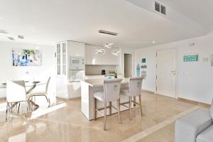 a white kitchen with white chairs and a table at CasaBella Marina Duquesa in Manilva +10 photos