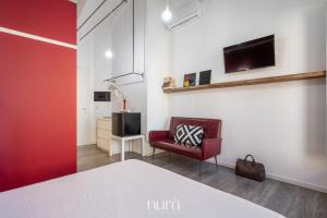 a living room with a red chair and a tv at Wine Passion Room in Quartu SantʼElena