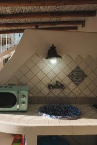 a kitchen with a counter with a toaster and a tile wall at Labottega home in Lipari