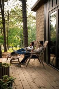 a group of three people sitting in chairs on a patio at Glamping cabin with private deck and hot tub! in Guntersville