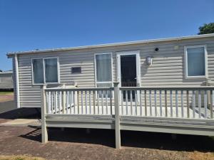 a mobile home with a porch and a white railing at Glendale Holiday Park in Wigton