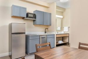 a kitchen with blue cabinets and a table and a refrigerator at City Express by Marriott Elkridge in Elkridge
