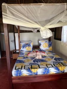 a bed with a canopy and pillows on it at Lokobe Djema Forest Lodge in Nosy Be