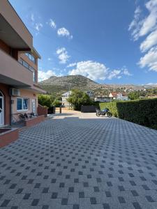 a driveway in front of a building with mountains in the background at Apartmani Slađo in Trebinje