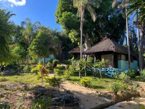 a small house with a thatched roof in a garden at Lokobe Djema Forest Lodge in Nosy Be