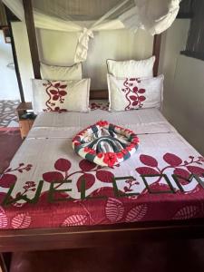 a bed with a red and white blanket on it at Lokobe Djema Forest Lodge in Nosy Be