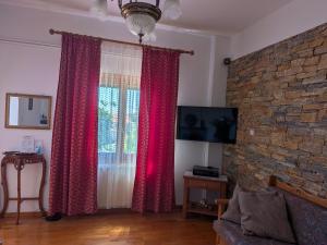 a living room with red curtains and a brick wall at Georgia House Portaria in Portaria