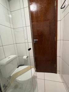 a bathroom with a toilet and a wooden door at Quarto com Ar Condicionado e banheiro no centro in Montes Claros