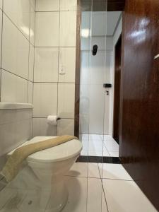 a bathroom with a toilet and a glass shower at Quarto com Ar Condicionado e banheiro no centro in Montes Claros