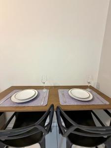 a wooden table with two chairs and two wine glasses at Apto com 2 quartos e A/C no Centro e Santa Casa in Montes Claros