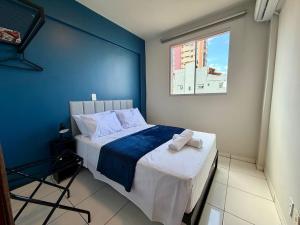 a bedroom with a bed with a blue wall at Apto com 2 quartos e A/C no Centro e Santa Casa in Montes Claros