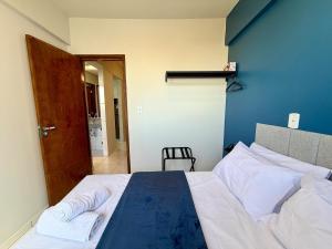 a bedroom with a bed with white sheets and a blue wall at Apto com 2 quartos e A/C no Centro e Santa Casa in Montes Claros +42 photos